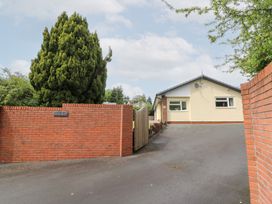 A house with a tree and brick wall at New Peny in Llandrindod Wells