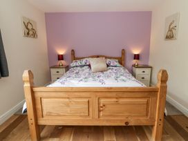 A bedroom featuring a wooden bed with floral bedding at New Peny in Llandrindod Wells