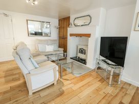 A living room with a sofa, coffee table, and television at Preswylfa Apartment in Caernarfon