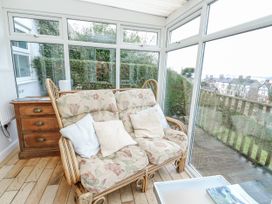 A conservatory with a sofa and a side table at Preswylfa Apartment in Caernarfon