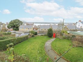 A garden with a pathway and houses in the background at Preswylfa Apartment in Caernarfon