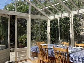 A dining table with plates and glasses in a glass conservatory at Sant Seiriol in Beaumaris
