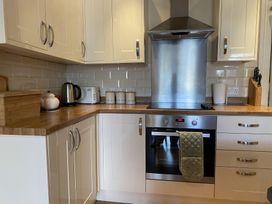A kitchen with white cabinets wooden countertops a stainless steel oven and stove with a hood and various kitchen items on the counter at Sant Seiriol in Beaumaris