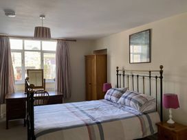 A bedroom with a bed desk chair wardrobe bedside table and lamps at Sant Seiriol in Beaumaris