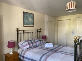 A bedroom with a double bed with checked bedding two bedside tables with lamps and a framed picture on the wall at Sant Seiriol in Beaumaris