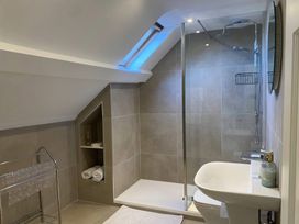 A bathroom with a walk-in shower under a sloped ceiling with a skylight and a white sink at Sant Seiriol in Beaumaris