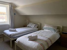 A bedroom with two single beds with striped bedding and bedside tables near a window at Sant Seiriol in Beaumaris