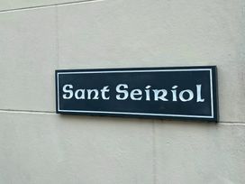 A black and white sign reading Sant Seiriol on a wall at Sant Seiriol in Beaumaris