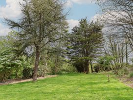 A garden with trees and grass at Erin Cottage in Pelynt near Looe