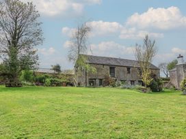 A garden with a stone building and trees at Hook Cottage in Pelynt near Looe