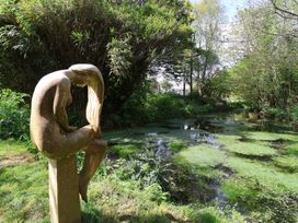 A sculpture near a pond surrounded by greenery at Hook Cottage Pelynt near Looe