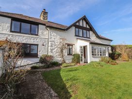 Exterior view of a white stone house with multiple windows a green lawn and a garden path at Cymryd Uchaf in Conwy