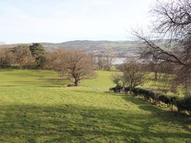 A grassy field with scattered trees and hills in the background at Cymryd Uchaf in Conwy