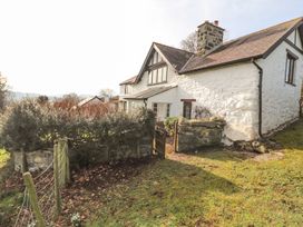 An exterior view of a white stone cottage with a chimney a small garden gate and fence at Cymryd Uchaf in Conwy
