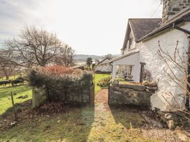 A stone house with a garden gate and bushes overlooking a green landscape at Cymryd Uchaf in Conwy