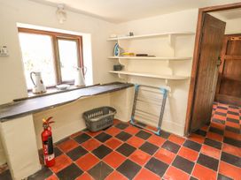 A utility room with a laundry basket fire extinguisher and drying rack near shelves and a window at Cymryd Uchaf in Conwy
