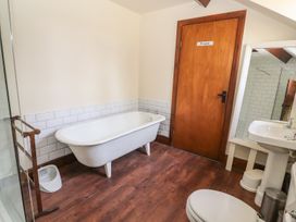 A bathroom with a bathtub toilet sink mirror and wooden door at Cymryd Uchaf in Conwy