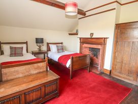 A bedroom with two single beds a fireplace a wooden chest a lamp and a wooden wardrobe at Cymryd Uchaf in Conwy