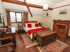 A bedroom with a wooden bed and chest wooden furniture and a fireplace at Cymryd Uchaf in Conwy