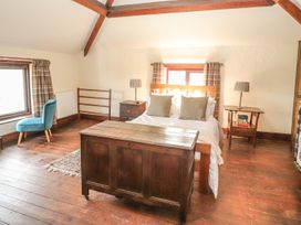 A bedroom with a wooden bed next to two bedside tables with lamps and a wooden chest at the foot of the bed at Cymryd Uchaf in Conwy