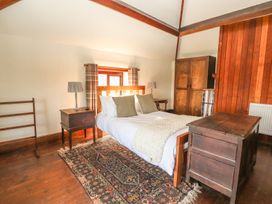 A bedroom with a bed two bedside tables lamps a wooden chest an armoire and a patterned rug at Cymryd Uchaf in Conwy