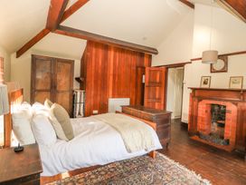A bedroom with a bed a wooden chest a fireplace and wardrobe at Cymryd Uchaf in Conwy