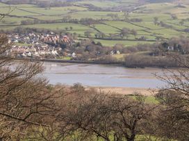 A view of a small town near a river with green fields and trees in the background at Cymryd Uchaf in Conwy