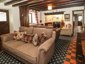 A living room with sofas cushions fireplace and wooden beams at Cymryd Uchaf in Conwy