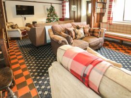 A living room with multiple sofas a Christmas tree a television and a bookshelf at Cymryd Uchaf in Conwy