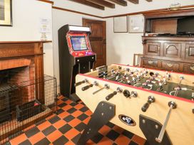 A game room with a foosball table arcade machine fireplace and wooden cabinet at Cymryd Uchaf in Conwy