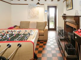 A game room with a foosball table sofa fireplace and a door to the outside at Cymryd Uchaf Conwy