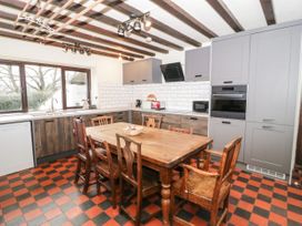 A kitchen with wooden table and chairs a checkered floor and gray and wooden cabinets at Cymryd Uchaf in Conwy