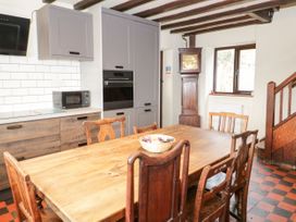 A kitchen with a wooden dining table and chairs a microwave oven and a tall wooden grandfather clock at Cymryd Uchaf in Conwy