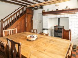 A dining room with wooden table and chairs next to a fireplace and staircase at Cymryd Uchaf in Conwy