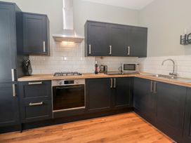 A kitchen with cabinets, an oven, stove, microwave, and sink at Molly's Cottage in Flookburgh