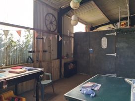 An indoor space with a table, chair, books, and a door at Owl Barn in Tavistock