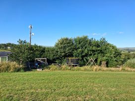 An outdoor area with grass, trees, and a trampoline at Owl Barn, Tavistock