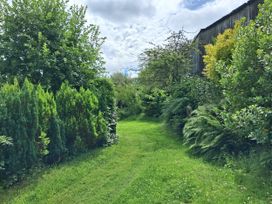 A garden path with grass and bushes at Owl Barn in Tavistock