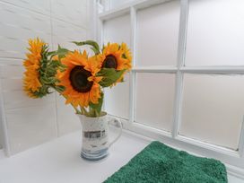 A bathroom with sunflowers in a pitcher and a green towel at 5 Old Sail Loft in Whitby