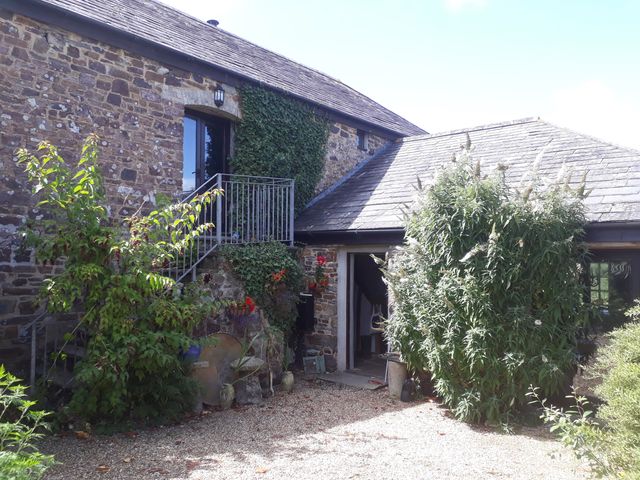 An exterior view of a stone building with outdoor stairs and plants around the entrance at Lazy Hare at Jens Orchard in St Giles On The Heath