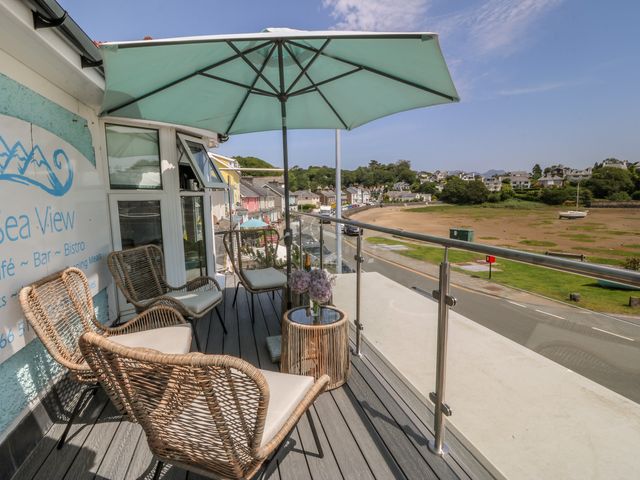 A balcony with chairs and a table overlooking the area at Bay View Apartment in Porthmadog