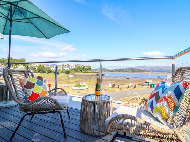 An outdoor area with chairs and a table overlooking water at Bay View Apartment in Porthmadog