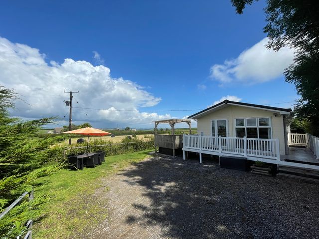 A house with a white porch and outdoor dining table with umbrella in a rural setting at Mountain View Lodge in Tavernspite near Narberth
