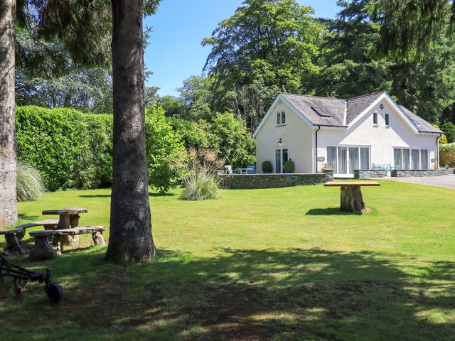 A house with benches and a table in a garden at Lakeside Cottage Ecclerigg near Ambleside