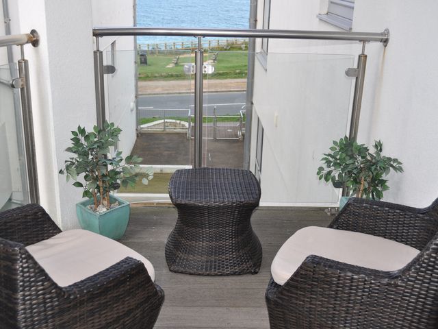 A balcony with chairs and a table overlooking the sea at 28 Zenith Porth