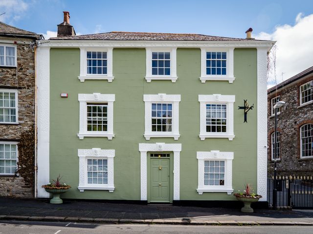A green building with white trim and multiple windows at The Meeting House in Ashburton
