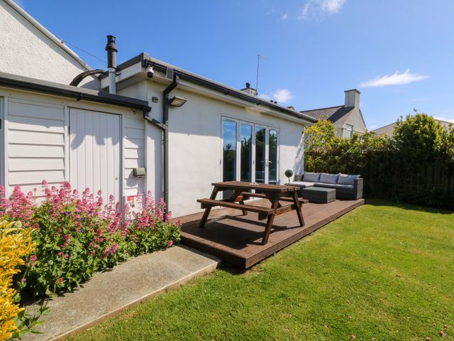 A house with a patio and flowerbed at Farm Cottage in Cemaes Bay
