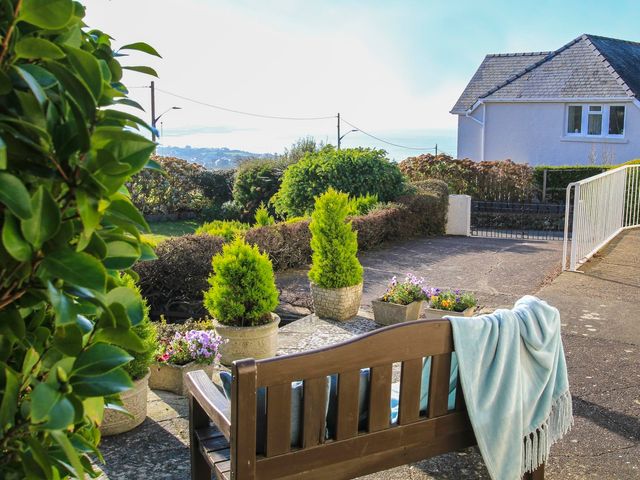 A garden with potted plants and flowers and a wooden bench with a blanket at Garnedd Lwyd in Llanfair
