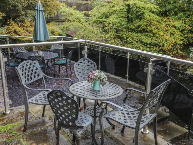 An outdoor seating area with metal tables and chairs a flower vase on the table and green foliage in the background at Melin y Coed Menai Bridge