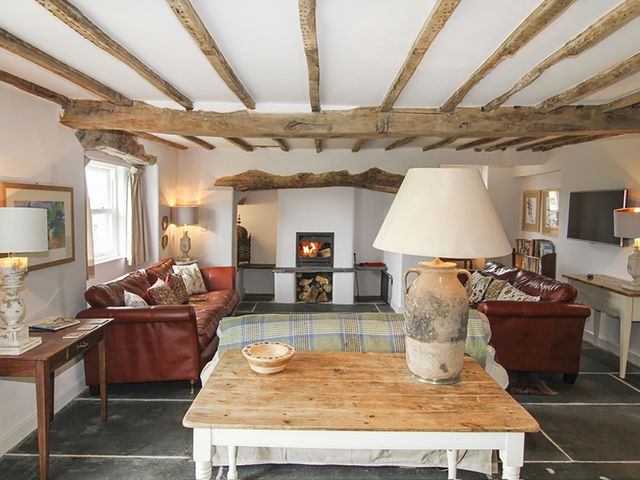 A living room with exposed wooden beams two red leather sofas and a fireplace at Ty Mawr Porthmadog in Porthmadog